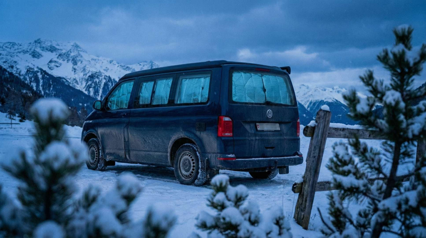 Wintercamping im Büssli: VW California Style Campervan im Schnee mit warmem Licht am Abend