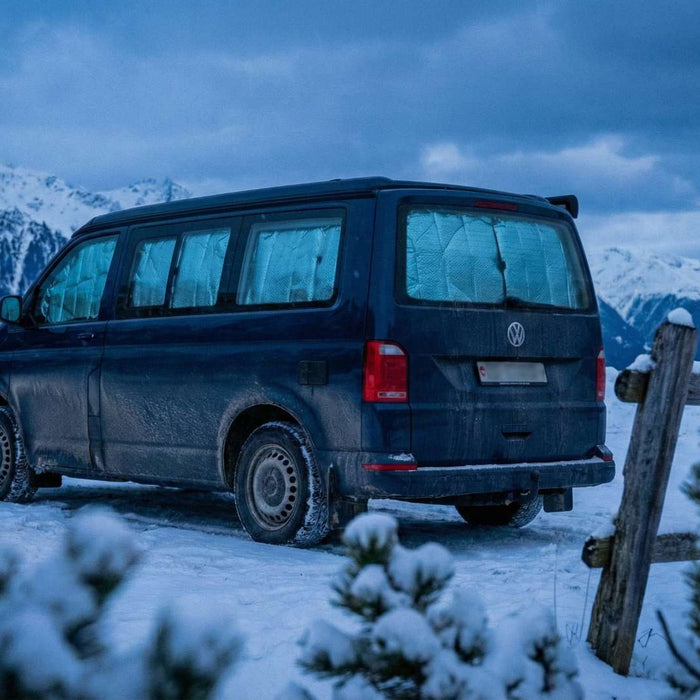 Wintercamping im Büssli: VW California Style Campervan im Schnee mit warmem Licht am Abend